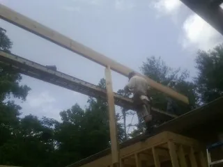 Carpenter setting a ridge beam over a new addition frame — Ice Dam Removal by Roofing Brothers in Spencerport