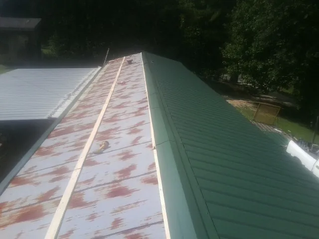 Old rusted panels beside newly installed green metal roofing — Wind Damage Roof Repair by Roofing Brothers in Spencerport