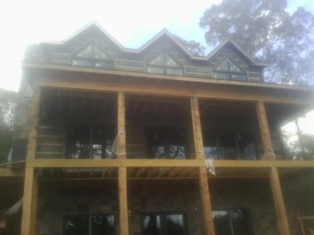 Dormers and porch framing on a large log home under construction — Roof Coating work by our crew in Spencerport