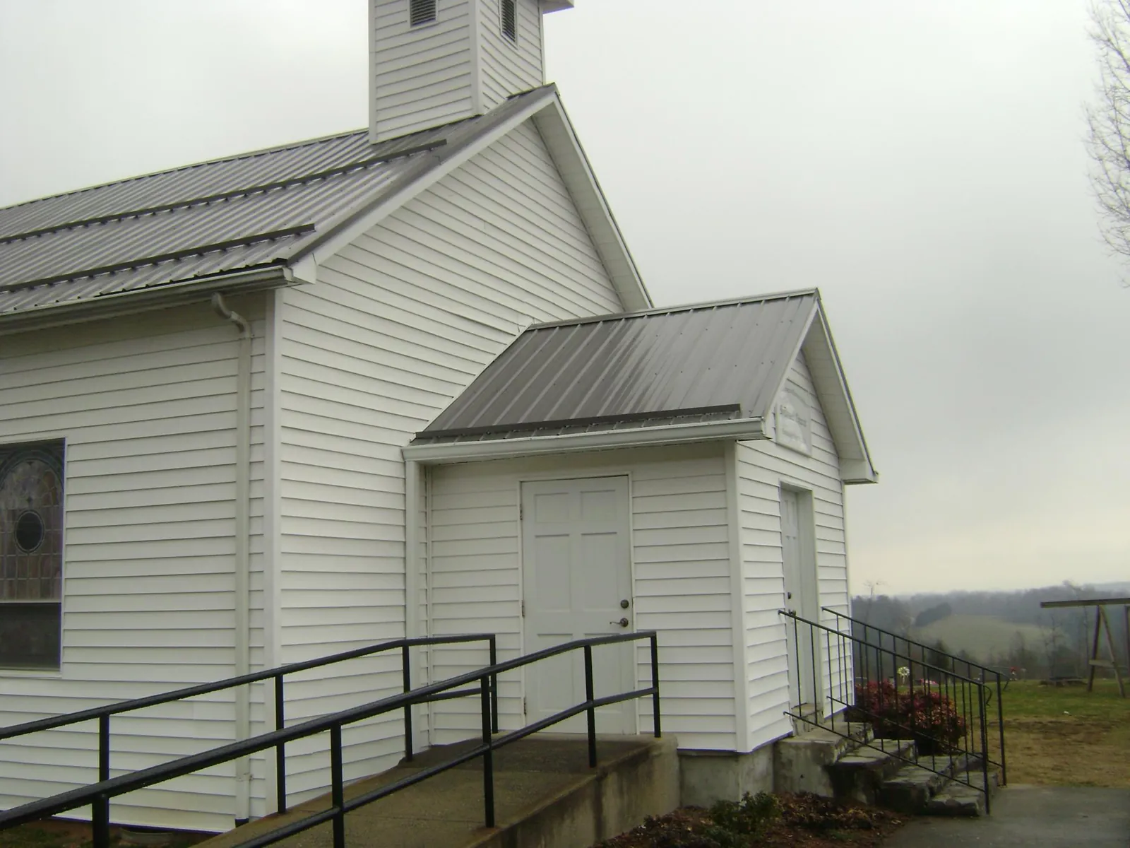 Gray metal roof on a white clapboard church with a steeple in Spencerport