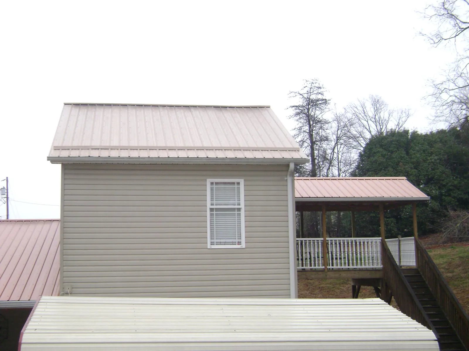 Tan metal roofs on a two story addition and attached porch, from a Roof Replacement job in Spencerport
