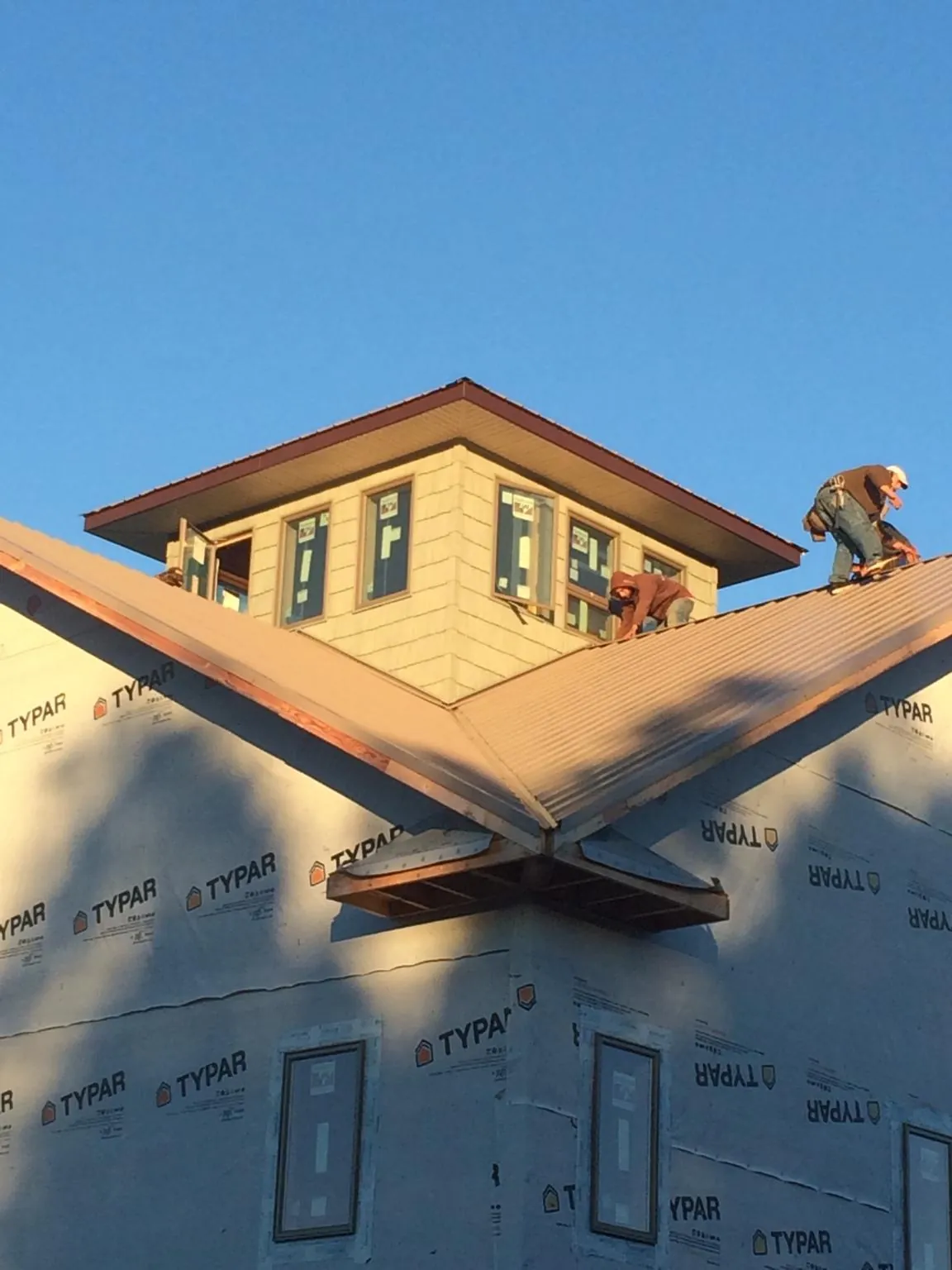 Roofers working around a rooftop cupola on a new metal roof at sunset — Roof Waterproofing in Spencerport by Roofing Brothers